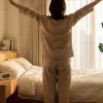 সকালে জেগে সতেজ হয়ে স্ট্রেচ করা একজন মানুষ, সূর্যালোক, পানি এবং পরিচ্ছন্ন ঘরের সাথে, ঘুম ও অলসতা দূর করার প্রতীক।