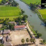 "রাজবাড়ী জেলার এ্যারিয়াল দৃশ্য, নদী, সবুজ ক্ষেত, স্থানীয় বাড়ি এবং সাংস্কৃতিক উপাদান সহ।"